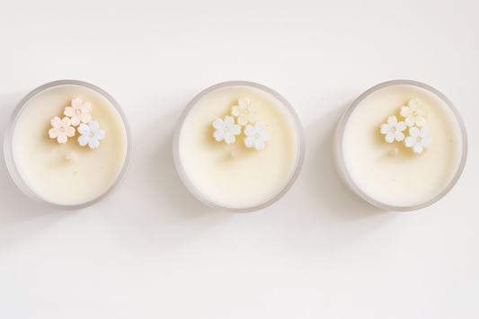 Three small jars of cream with flower petals on a white background